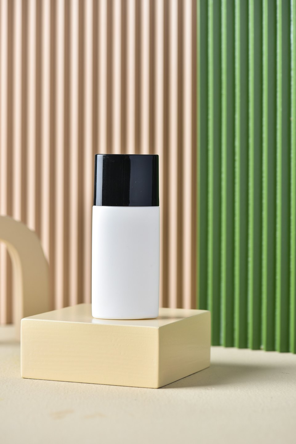 A skincare bottle sits centered on a yellow pedestal.